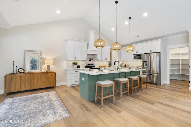 kitchen with white cabinets, appliances with stainless steel finishes, hanging light fixtures, light countertops, and a kitchen bar