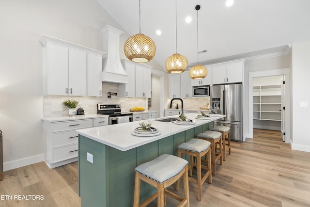 kitchen featuring a breakfast bar area, a sink, white cabinets, light countertops, and appliances with stainless steel finishes