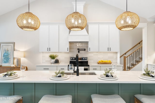 kitchen with decorative light fixtures, electric range, a kitchen breakfast bar, and white cabinetry