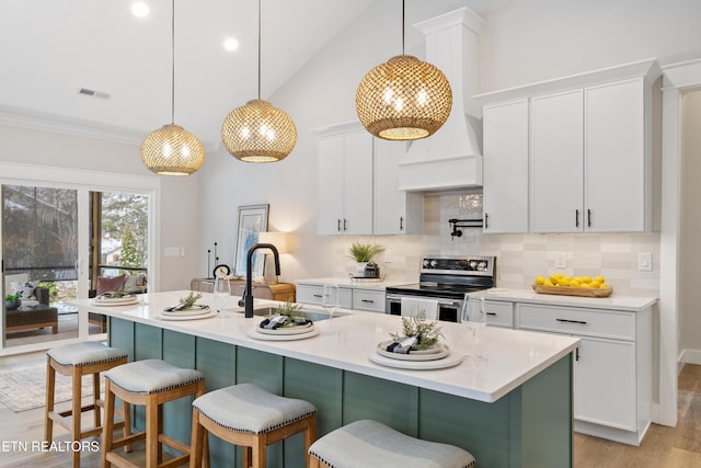 kitchen featuring electric stove, light countertops, white cabinets, a sink, and a kitchen breakfast bar