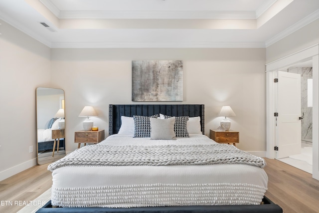 bedroom with a raised ceiling, light wood-style flooring, and crown molding