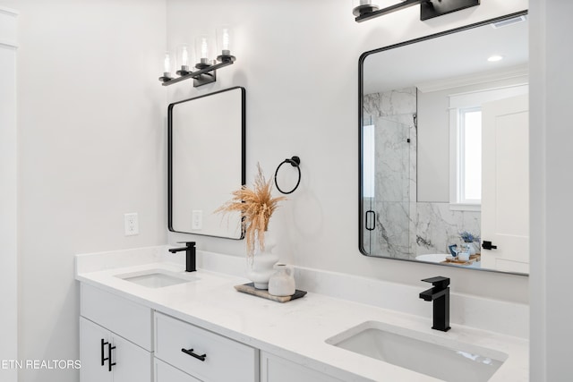 bathroom featuring double vanity, a marble finish shower, and a sink