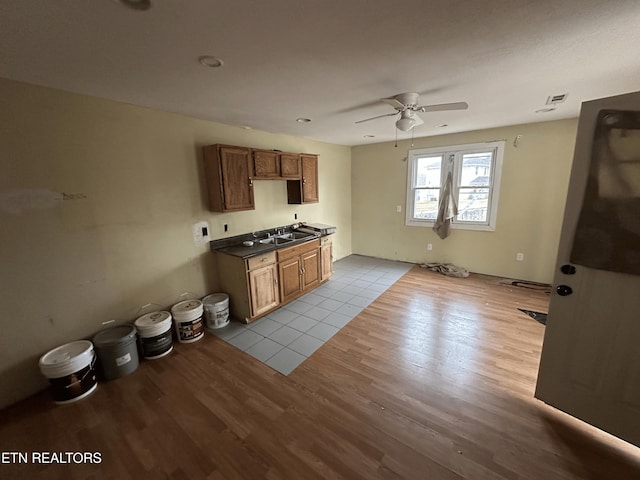 kitchen featuring sink, ceiling fan, and light wood-type flooring