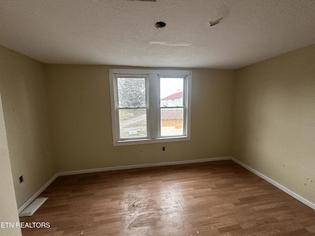 unfurnished room featuring hardwood / wood-style flooring and a textured ceiling