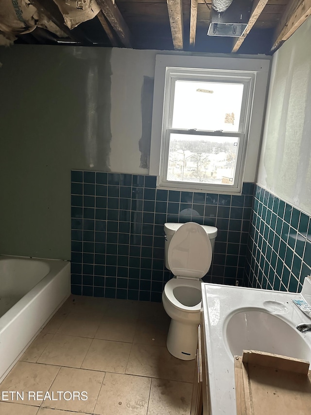 bathroom with tile walls, vanity, toilet, a bath, and tile patterned floors