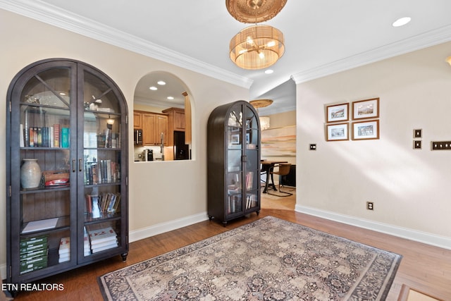 living area with crown molding, a chandelier, and dark hardwood / wood-style flooring