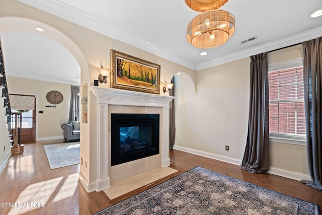 living room with arched walkways, plenty of natural light, hardwood / wood-style flooring, and ornamental molding