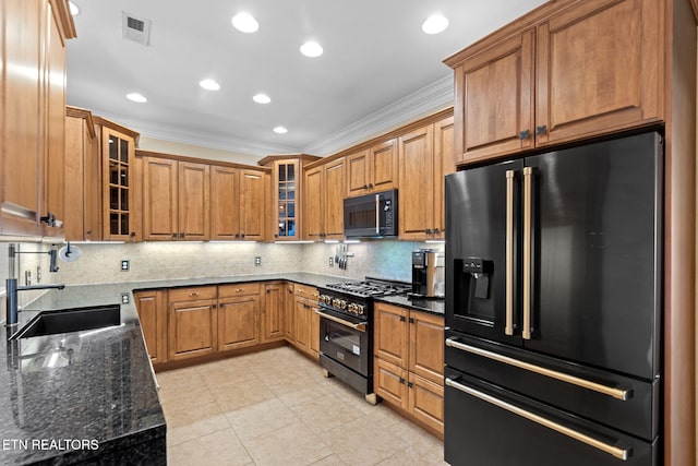 kitchen with visible vents, crown molding, dark stone counters, black appliances, and a sink