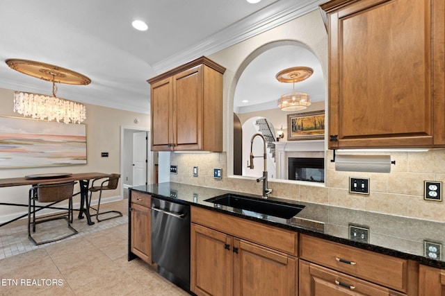 kitchen featuring sink, hanging light fixtures, ornamental molding, stainless steel dishwasher, and dark stone counters