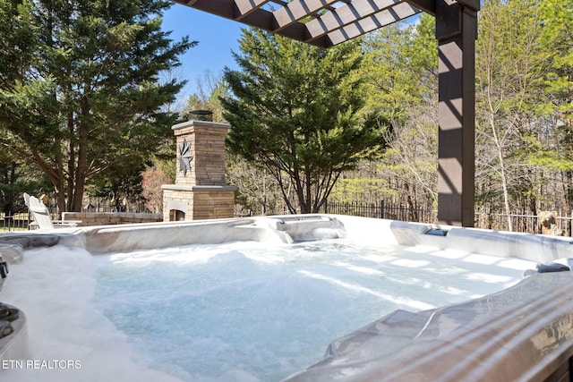 details featuring a jacuzzi, an outdoor stone fireplace, and fence