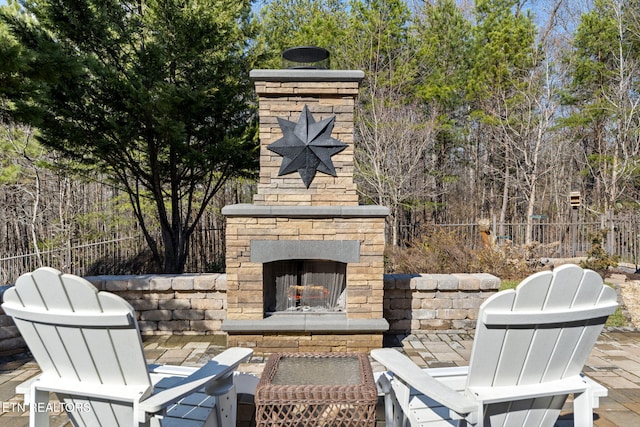 view of patio with fence and an outdoor stone fireplace