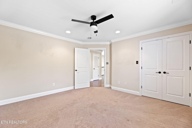 unfurnished bedroom with a closet, crown molding, baseboards, light colored carpet, and ceiling fan