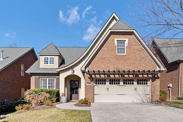 view of front of house with brick siding, a high end roof, driveway, and a garage