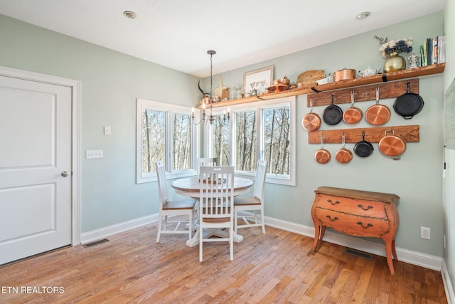 dining area with an inviting chandelier and light hardwood / wood-style flooring