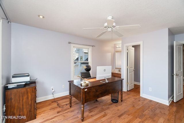 home office featuring ceiling fan, light hardwood / wood-style flooring, and a textured ceiling