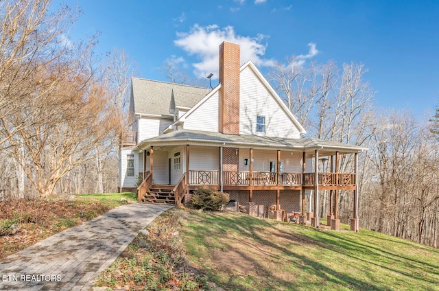 view of front of house featuring a porch, a chimney, and a front lawn