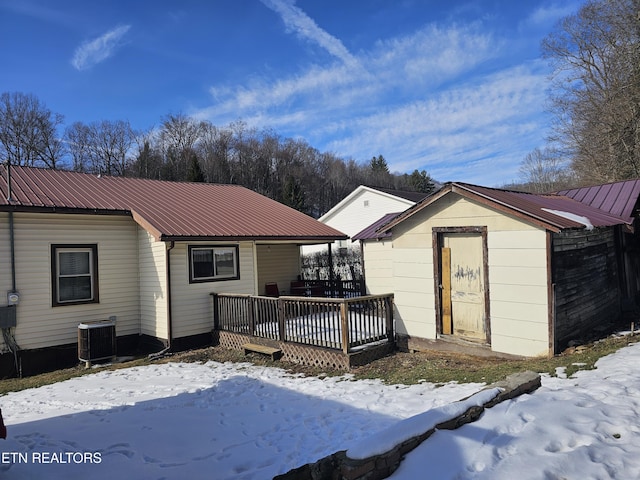 snow covered house featuring central AC unit and a deck