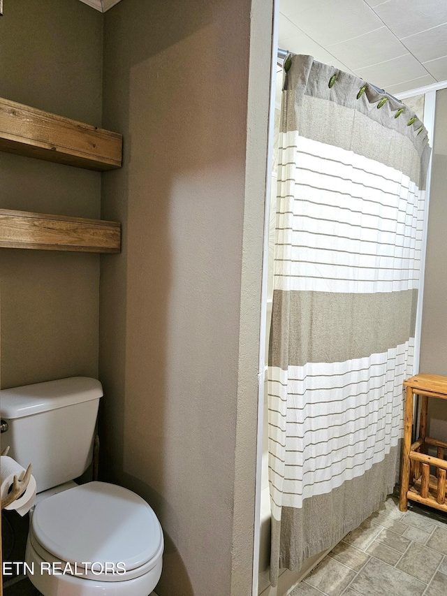 bathroom with shower / bath combination with curtain and toilet