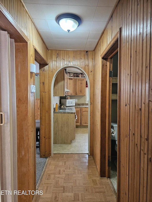 corridor featuring light parquet floors and wood walls