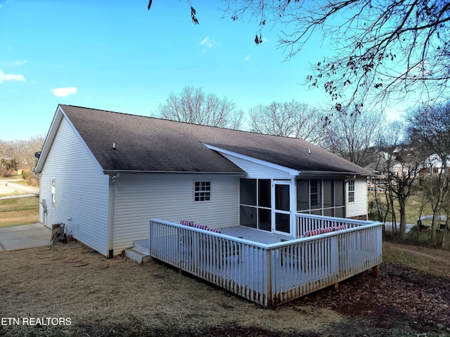 rear view of house featuring a wooden deck, a yard, and a sunroom