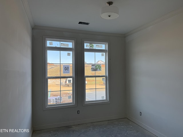 empty room with baseboards, concrete flooring, visible vents, and crown molding