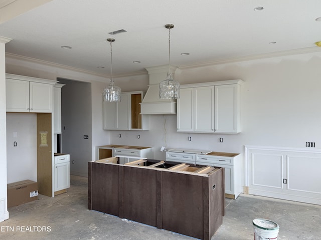 kitchen with custom range hood, a kitchen island, decorative light fixtures, crown molding, and concrete floors