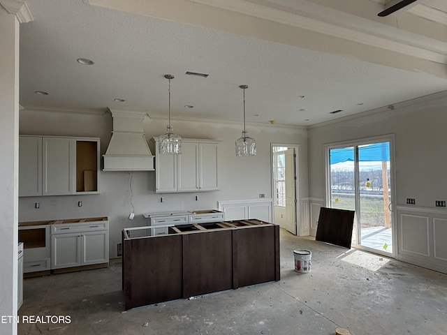 kitchen with a decorative wall, premium range hood, visible vents, ornamental molding, and wainscoting