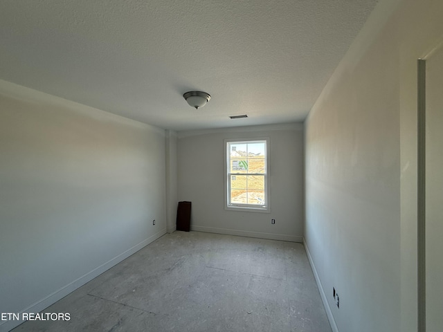 empty room featuring baseboards, visible vents, and a textured ceiling