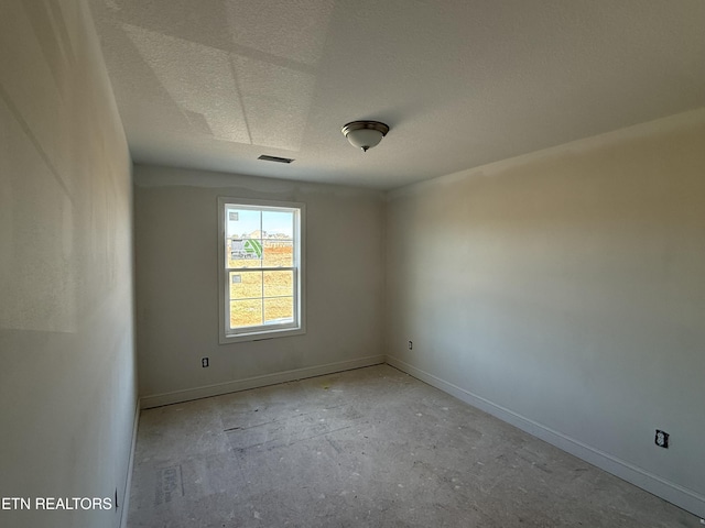 spare room featuring baseboards, visible vents, and a textured ceiling