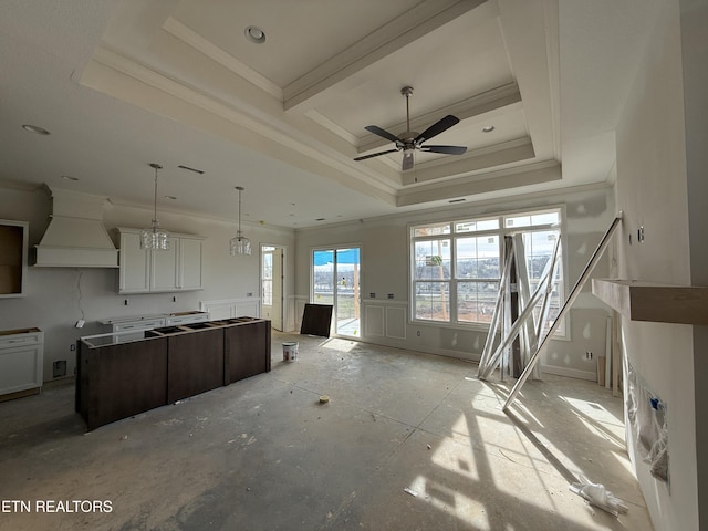 kitchen featuring a tray ceiling, custom exhaust hood, a kitchen island, and crown molding