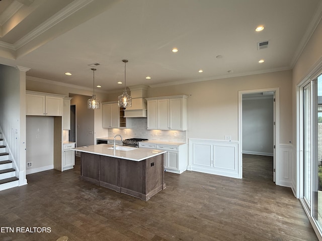 kitchen featuring a kitchen island with sink, recessed lighting, light countertops, white cabinets, and a sink