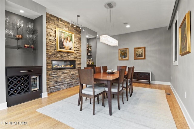 dining room with a stone fireplace and light wood-type flooring