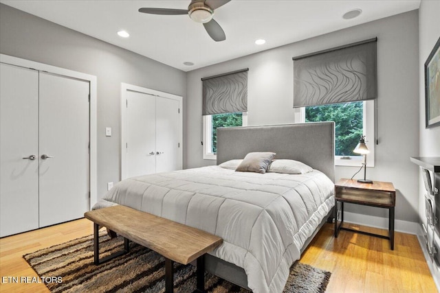 bedroom with ceiling fan, light wood-type flooring, and two closets