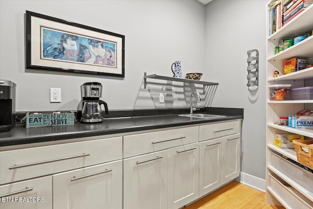 interior space with white cabinetry, sink, and light hardwood / wood-style flooring