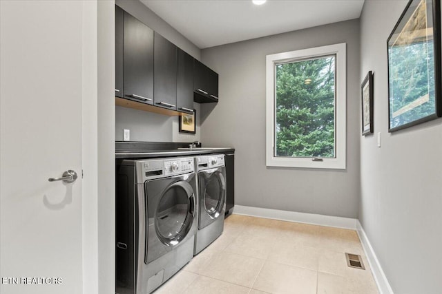 washroom featuring independent washer and dryer, cabinets, and light tile patterned flooring