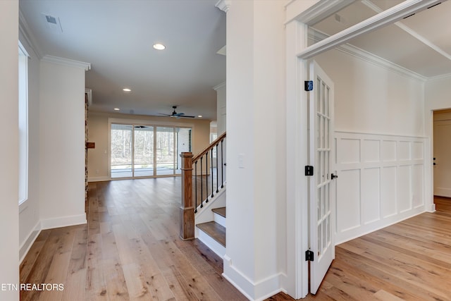 corridor with ornamental molding and light hardwood / wood-style floors