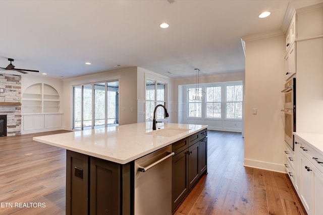 kitchen with white cabinetry, stainless steel appliances, sink, and a center island with sink