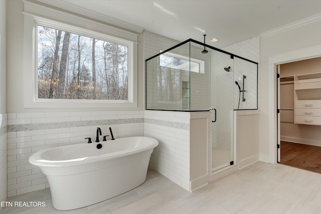 bathroom featuring crown molding, separate shower and tub, and tile walls