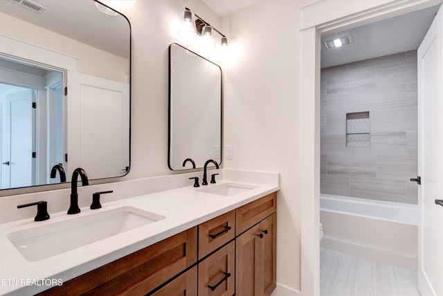 full bathroom featuring vanity, tiled shower / bath combo, and toilet