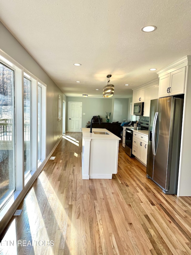 kitchen with range with electric stovetop, pendant lighting, white cabinetry, sink, and stainless steel fridge