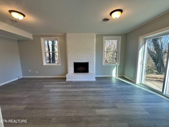 unfurnished living room with dark hardwood / wood-style flooring, a fireplace, crown molding, and a wealth of natural light