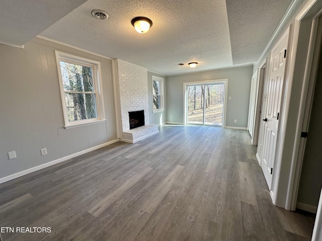 unfurnished living room with dark hardwood / wood-style flooring, a brick fireplace, and a textured ceiling