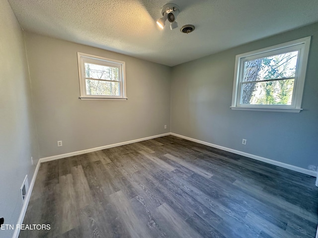 spare room featuring dark hardwood / wood-style flooring and a textured ceiling