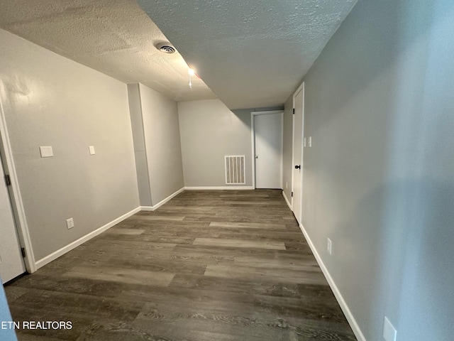 hall featuring dark wood-type flooring and a textured ceiling