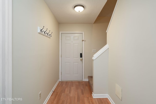 doorway with light hardwood / wood-style floors and a textured ceiling