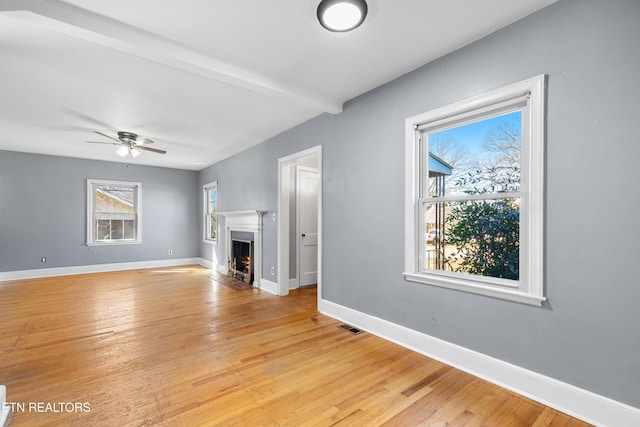 unfurnished living room with beamed ceiling, ceiling fan, and light hardwood / wood-style floors