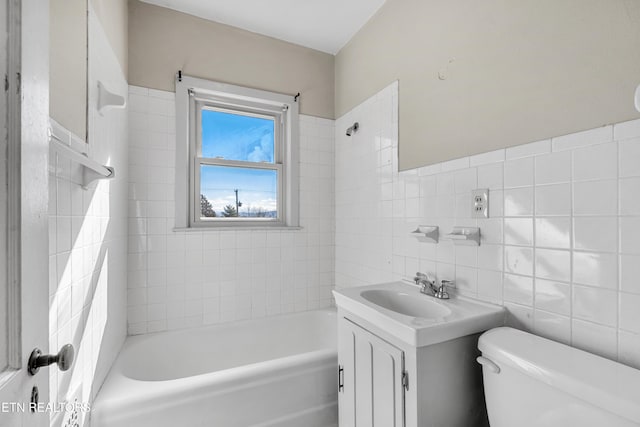 full bathroom with vanity, toilet, tiled shower / bath combo, and tile walls