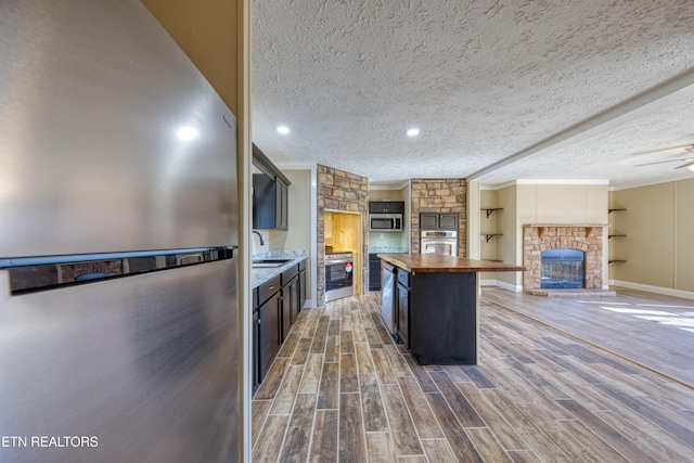 kitchen with sink, a center island, a textured ceiling, and appliances with stainless steel finishes