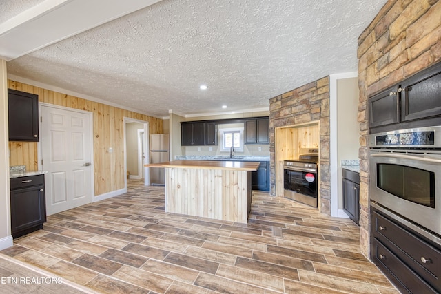 kitchen with dark brown cabinets, a textured ceiling, and appliances with stainless steel finishes