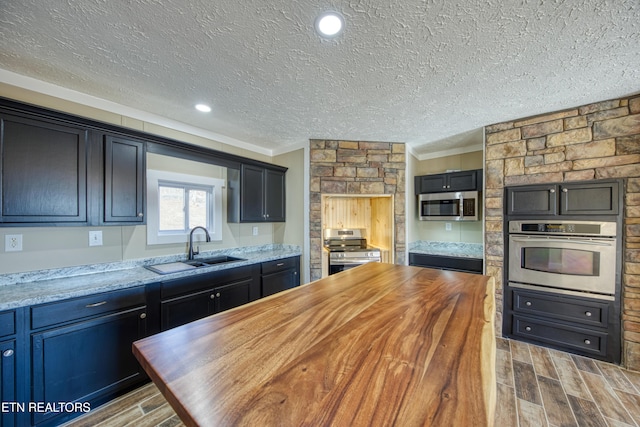 kitchen with light stone counters, stainless steel appliances, crown molding, and sink